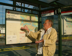 Älterer Mann steht hilflos auf einem Bahnsteig vor einem Fahrplanaushang